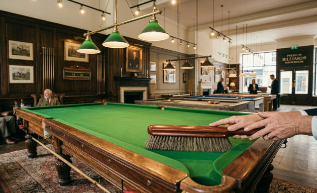Mains entretenant un tapis de billard avec une brosse